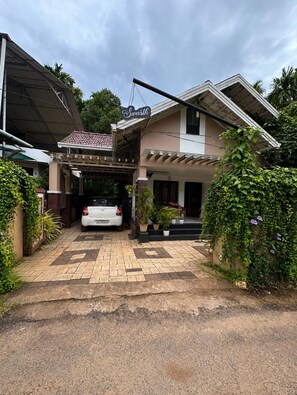 Ein zweigeschossiges Haus mit einem Auto auf der Auffahrt, umgeben von viel Grün.