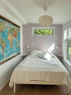 A bedroom with a bed, a world map on the wall, a window, and a ceiling light. - Summer cottage with orangery and garden, Falster (Væggerløse)