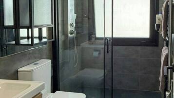 Un baño moderno con ducha de vidrio, inodoro y lavamanos.