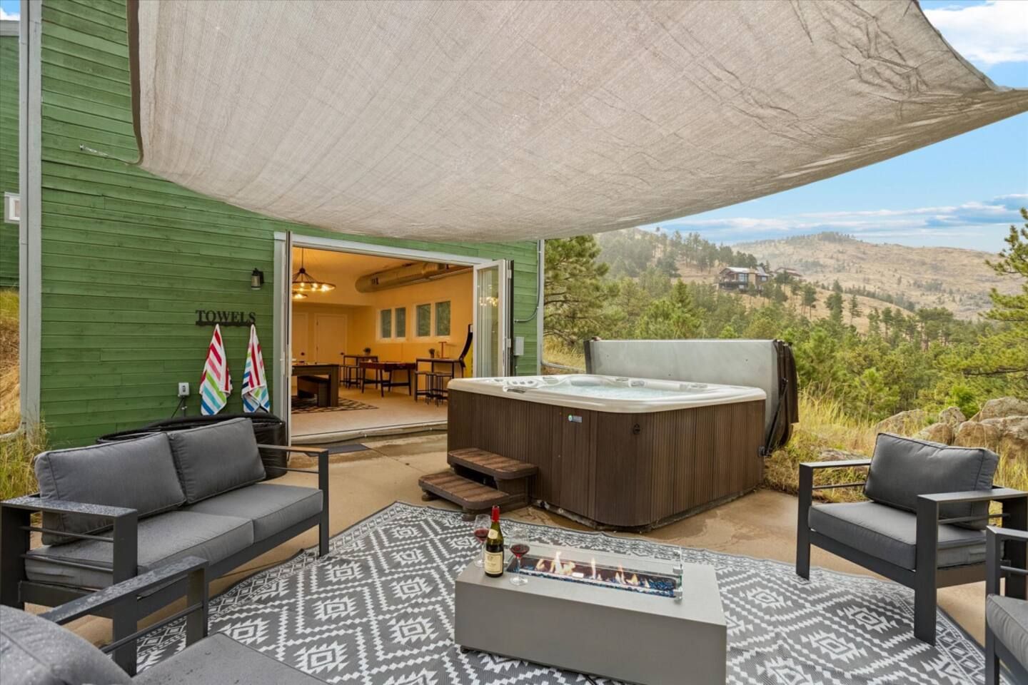 An outdoor patio with a hot tub, sofas, and a fire feature.