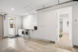 Ein moderner Waschraum mit Waschmaschine, Trockner und einem großen weißen Schrank.