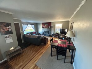 A living room with a sofa, a fireplace, a television, and a dining area with chairs and a table. - Millcreek MTN Home. - 2 bdm 1 bth, full kitchen, (Salt Lake City)