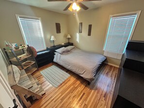 A bedroom with a bed, nightstands, a desk with a chair, a ceiling fan, and windows with blinds. - Millcreek MTN Home. - 2 bdm 1 bth, full kitchen, (Salt Lake City)
