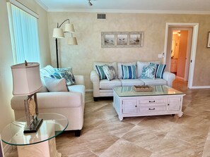 A living room with a sofa, armchair, glass coffee table, and floor lamp. - MB-near Beaches and IMG, Pool, Tennis, Pickleball (Bradenton)