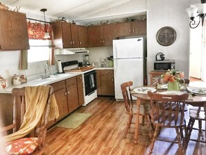 Una cocina con muebles de madera, un refrigerador blanco, un microondas y una mesa de comedor con sillas.