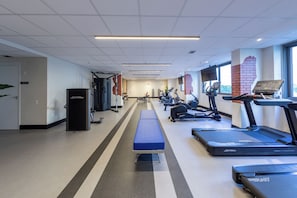 Un gimnasio con cintas de correr, bicicletas estáticas y máquinas de pesas.