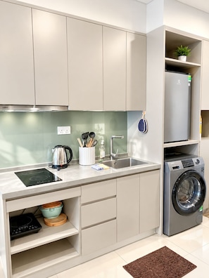 A modern kitchen with a built-in stove, sink, and a compact washer. - Man Seaside Homestay - The Song Vung Tau (Thanh pho Ho Chi Minh)