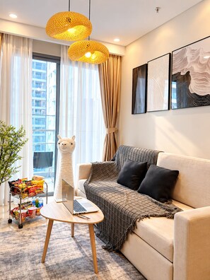 A modern living room with a sofa, a laptop on a small table, and a decorative llama statue. - Man Seaside Homestay - The Song Vung Tau (Thanh pho Ho Chi Minh)