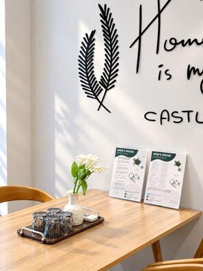 A dining area with a wooden table, a vase with flowers, and two informational signs titled 'MAN'S HOUSE'. - Man Seaside Homestay - The Song Vung Tau (Thanh pho Ho Chi Minh)