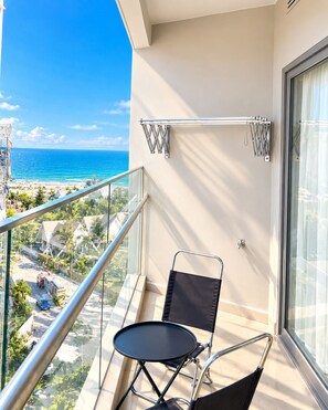 A balcony with a view of the ocean, a metal railing, a black chair, and a small table. - Man Seaside Homestay - The Song Vung Tau (Thanh pho Ho Chi Minh)