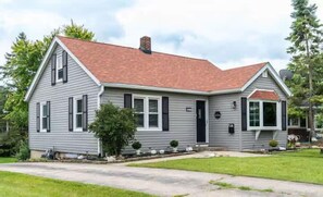 A single-story house with a red roof, a front porch, and a small front yard. - Lake Geneva Getaway Home | Walk to Downtown & Lake (Lake Geneva)