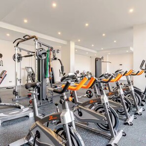 Een sportschool met diverse cardio-apparaten, gewichthefmaterialen en een spiegelwand.