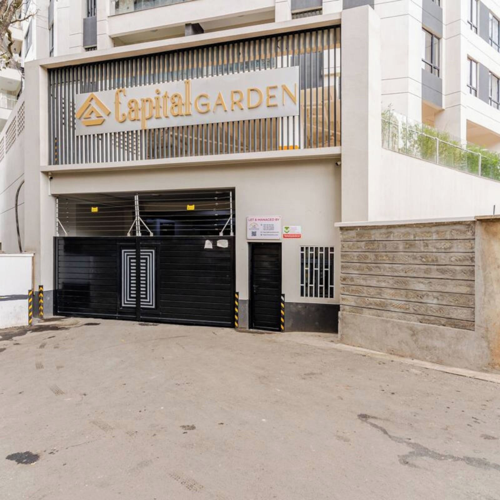 A building with a sign reading 'Capital Garden' and a gated entrance.
