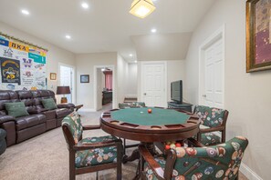 A living room with a pool table, a brown leather couch, and a wall decorated with various sports memorabilia.