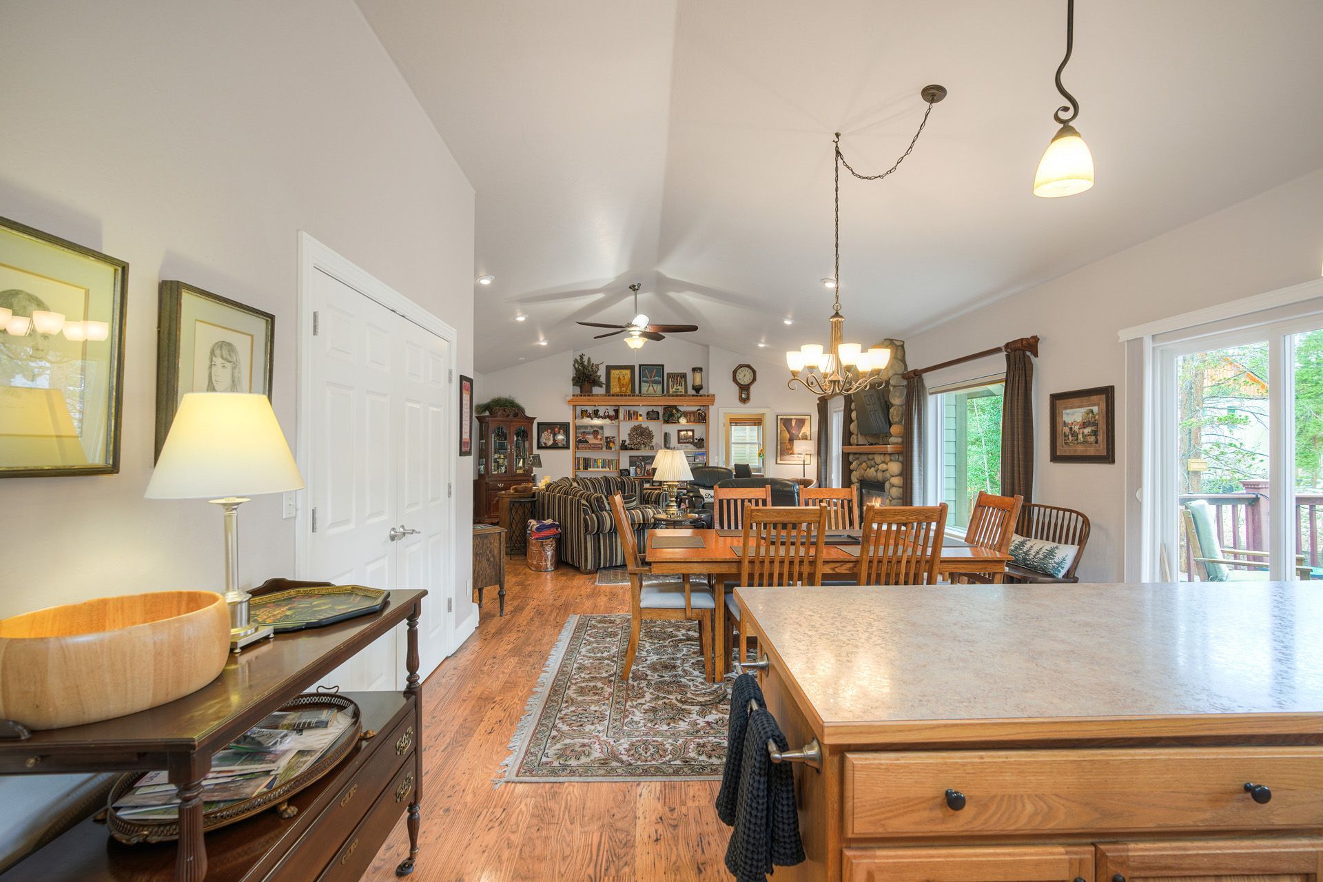 A spacious kitchen with a dining area, wooden furniture, and a stone fireplace.