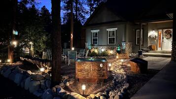A house with a stone fireplace, outdoor seating, and a well-lit porch.