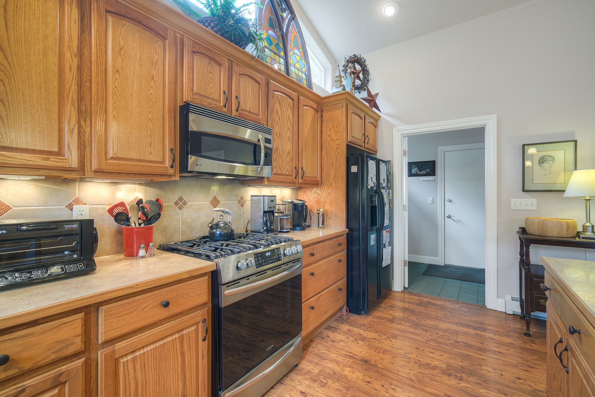 A kitchen with wooden cabinets, a stove, a microwave, a refrigerator, and a coffee maker.