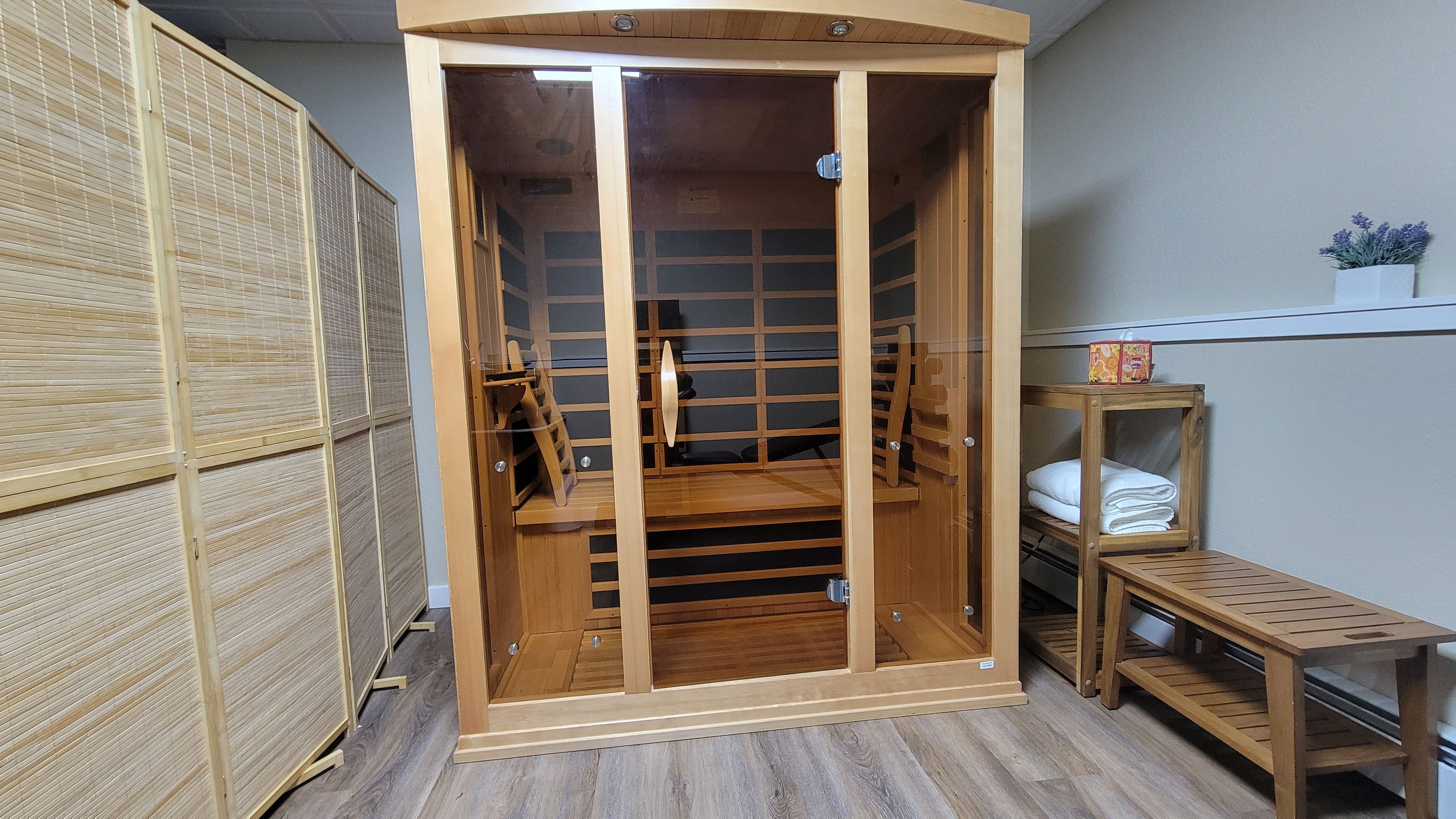 A room with a wooden wardrobe, a small wooden bench, and a shelf with folded towels.