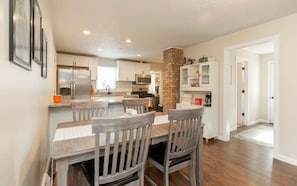 Una cocina moderna con una isla central, muebles blancos y una pared de ladrillo decorativa.