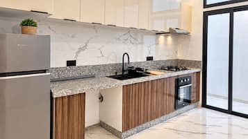 A modern kitchen with a marble countertop, stainless steel appliances, and wooden cabinetry.