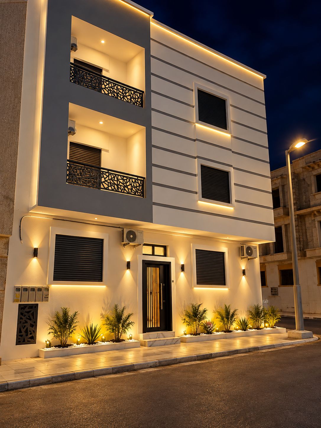 A modern two-story building with balconies, a central entrance, and outdoor lighting.