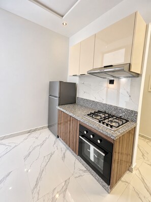 A compact kitchen with a built-in gas stove, oven, and a stainless steel refrigerator.