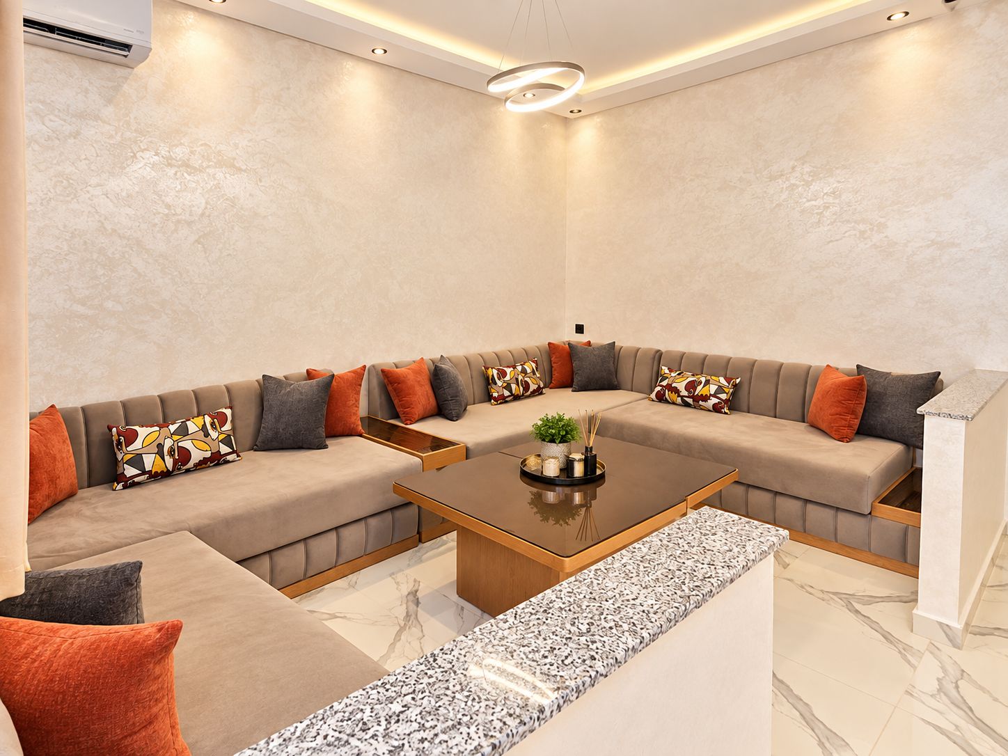 A modern living room with a sectional sofa, a coffee table, and a marble floor.