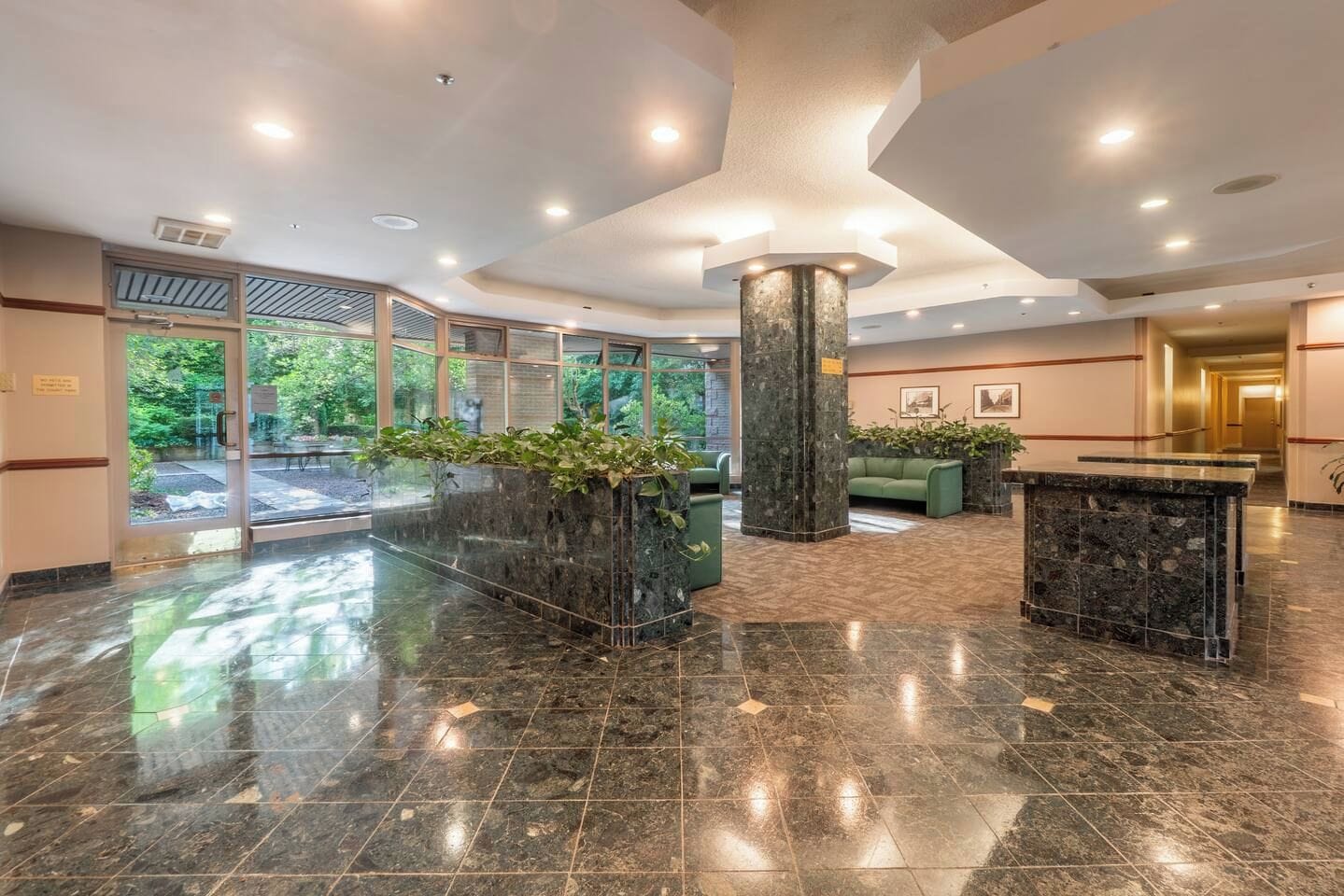 A lobby with a marble floor, a reception desk, and a large pillar.