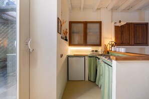 Eine kleine Küche mit Kühlschrank, Holzschränken und einem Fenster mit Blick.