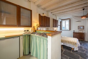 Cozinha compacta com uma ilha pequena, armários de madeira e piso de pedra.