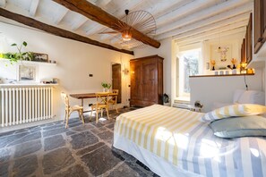 Ein Schlafzimmer mit einem Bett, einem Holztisch, einem Stuhl, einem Heizkörper und einem Fenster.