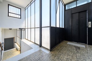 A room with large windows, a black door, and a tiled floor. - Palazzo De Sangro a Spaccanapoli, 3 camere (Naples)
