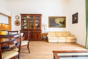 En stue med et træskab, en sofa, et spisebord med stole og et billede på væggen.