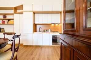 A compact kitchen with white cabinets, a wooden dining table, and a built-in oven. - Palazzo De Sangro a Spaccanapoli, 3 camere (Naples)