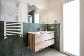 Ein Badezimmer mit einem Holzkosmetikschrank, einem Spiegel, einem Fön und einem Handtuchhalter.