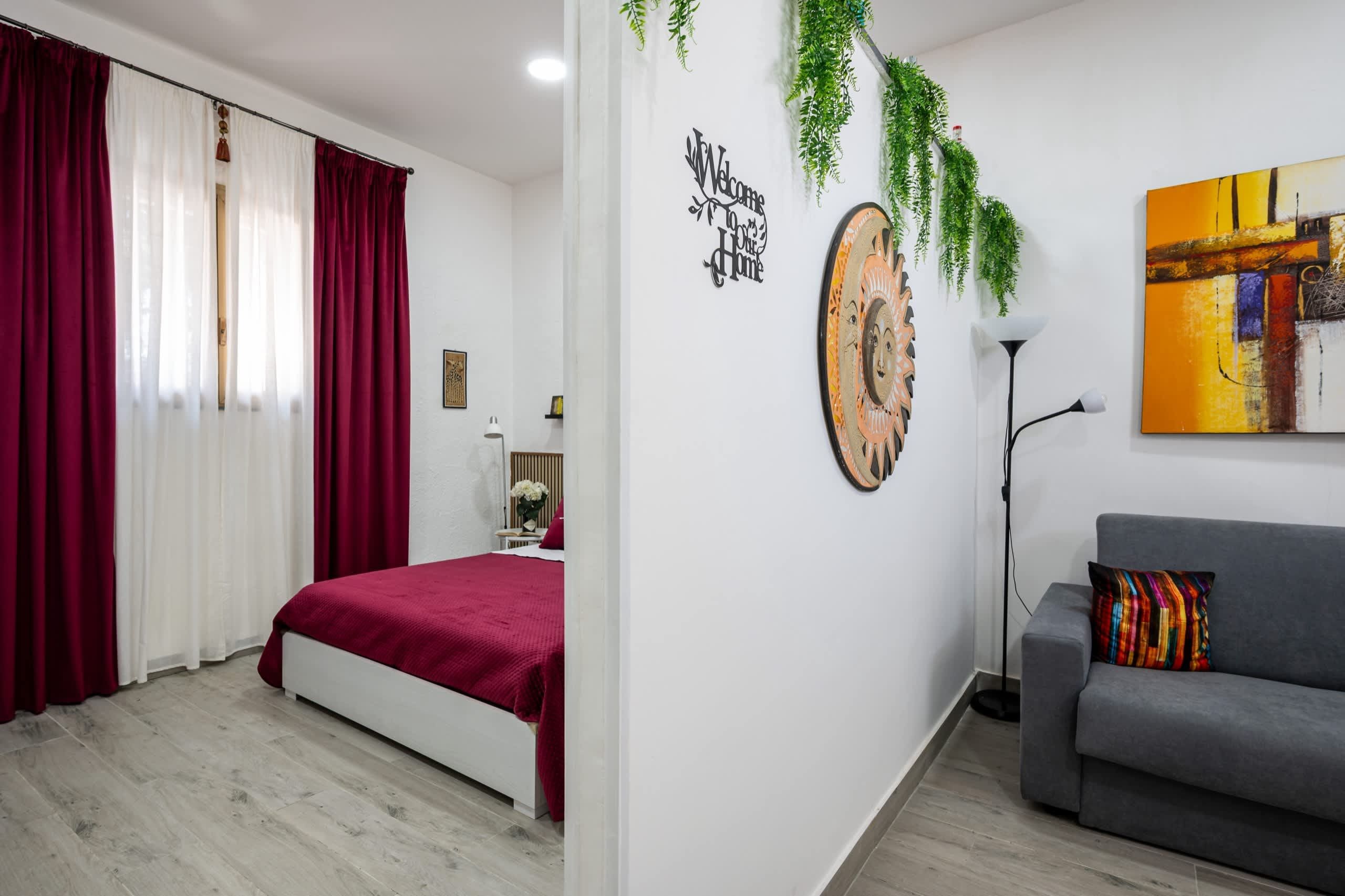 Ein modernes Schlafzimmer mit einem Bett, einem grauen Sofa, einer Wanduhr und einem Schild mit der Aufschrift 'Welcome Home'.