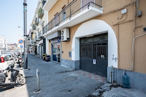 A street with parked cars and motorcycles, a no parking sign, and a building with a storefront. - 10 min dall'aeroporto - navetta - self check-in (Naples)