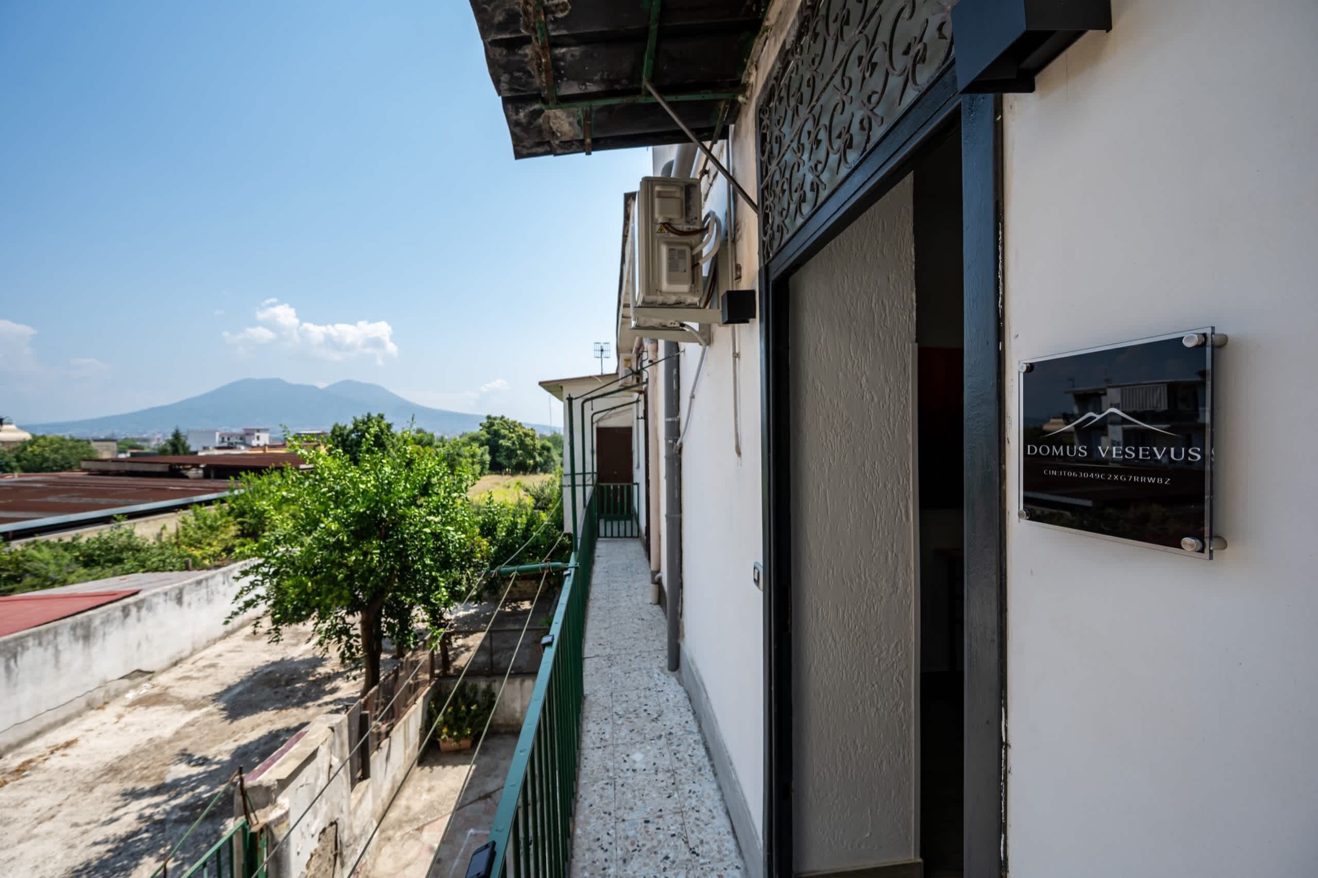 Un edificio con un cartello che riporta 'DOMUS VESEVUS' e una vista di una montagna sullo sfondo.