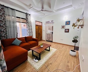 A living room with a sofa, a coffee table, and a potted plant. - Olive House (Dar es Salaam)
