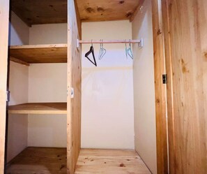 A wooden closet with a metal rod and hooks for hanging items. - Olive House (Dar es Salaam)