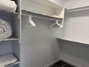 A walk-in closet with shelves and hanging space, containing folded blankets and a few hangers. - Spacious 3BR Duplex Near Edmonton Airport (Edmonton)