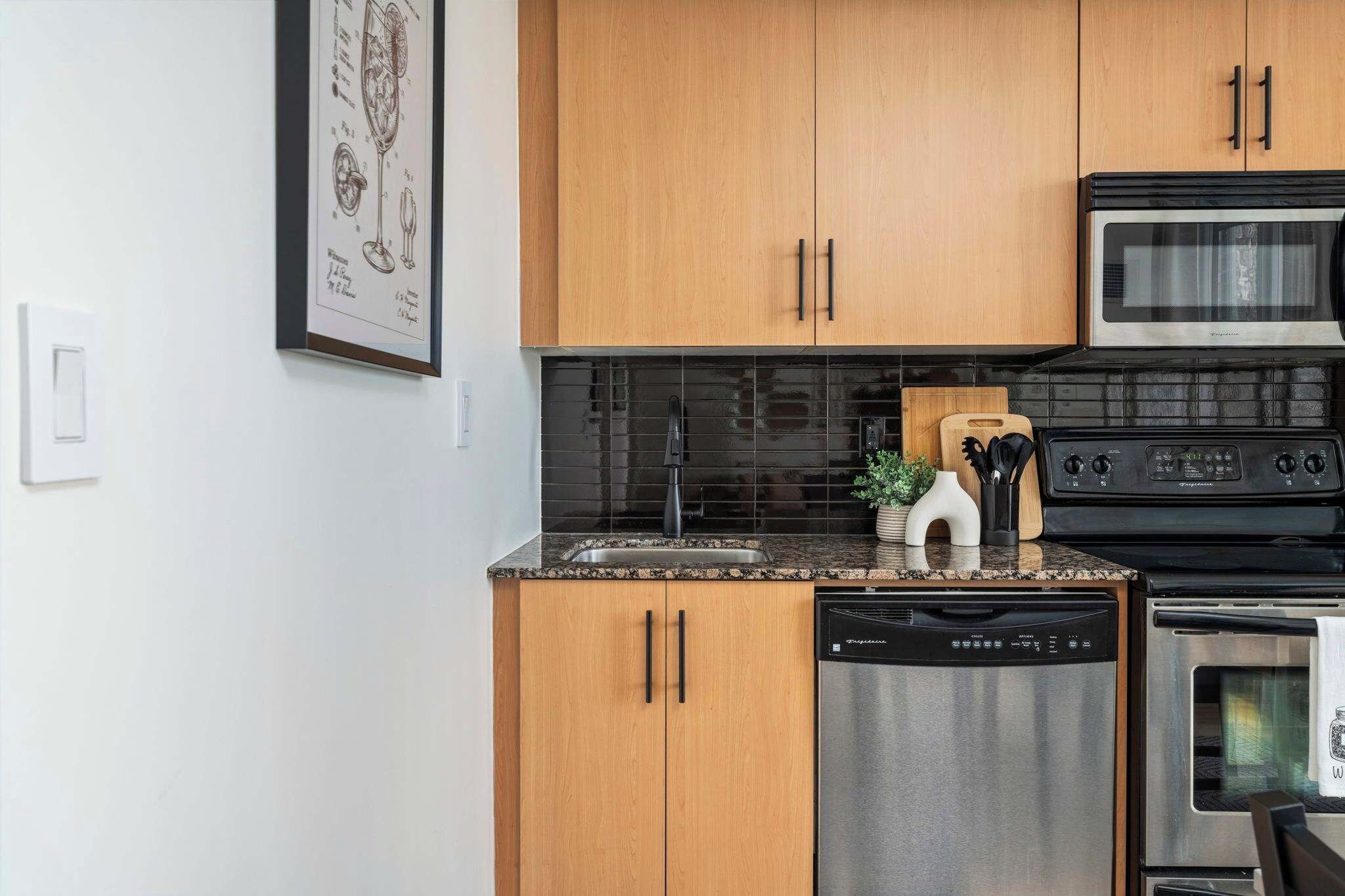Een keuken met houten kastjes, een roestvrijstalen vaatwasser, een magnetron en een fornuis.