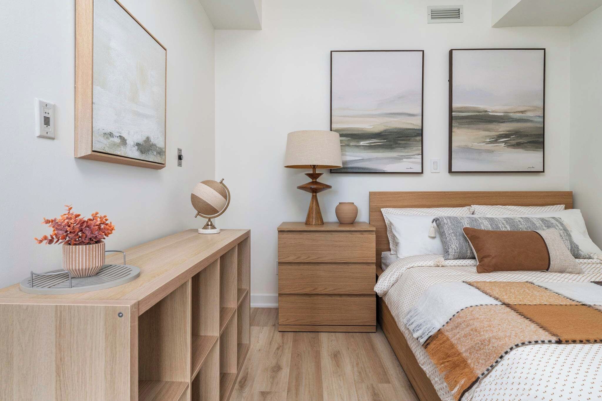 A bedroom with a bed, a bedside table, a lamp, a globe, and two framed pictures on the wall.