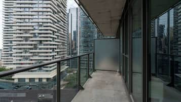 Un balcón con barandilla de vidrio que ofrece vistas a un paisaje urbano con edificios modernos.
