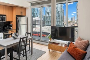 Een modern appartement met keuken, eethoek en woonkamer, voorzien van een groot raam met uitzicht over de stad.