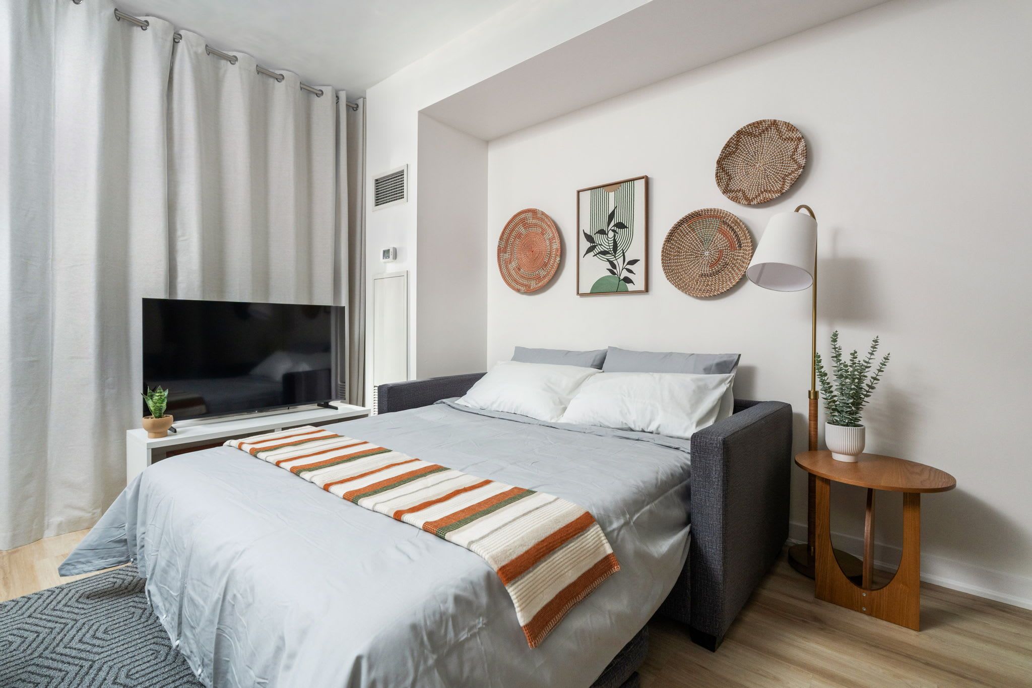 A modern bedroom with a bed, a TV, and a bedside table with a lamp.