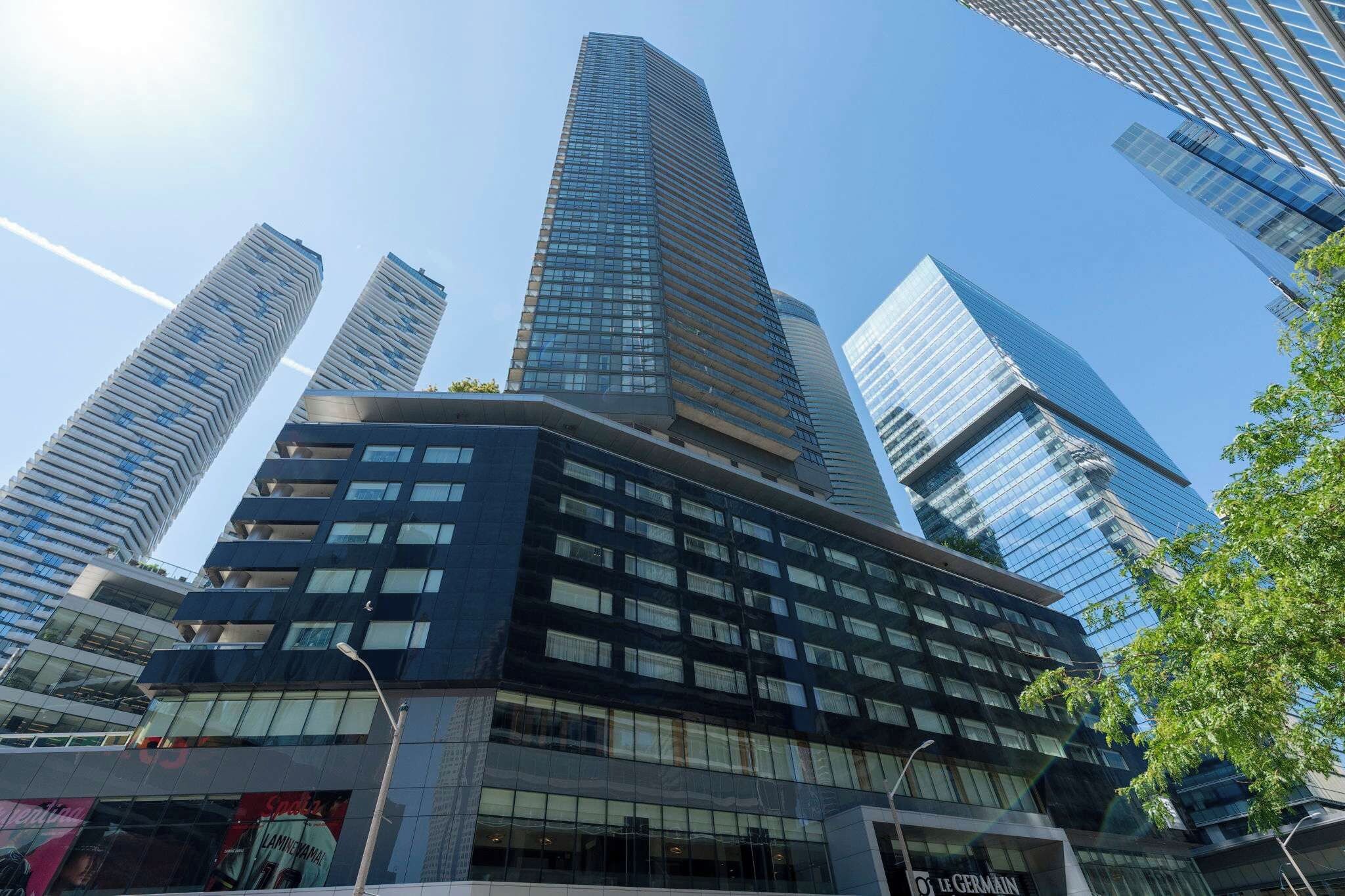 Un moderno edificio de gran altura con fachada de vidrio, rodeado de otros edificios altos.
