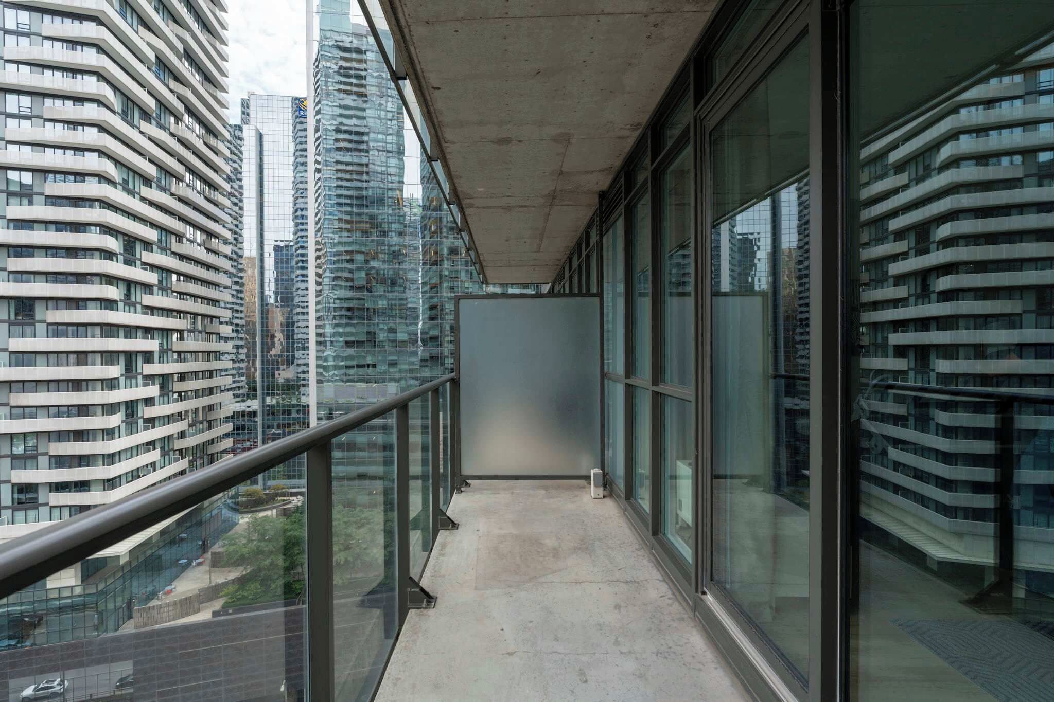 A balcony with a glass railing overlooking a cityscape with modern buildings.