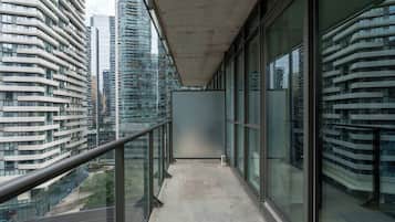 A balcony with a glass railing overlooking a cityscape with modern buildings.