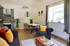 Ein modernes Wohnzimmer mit einer Couch, einem Esstisch und einer Küche im Hintergrund.